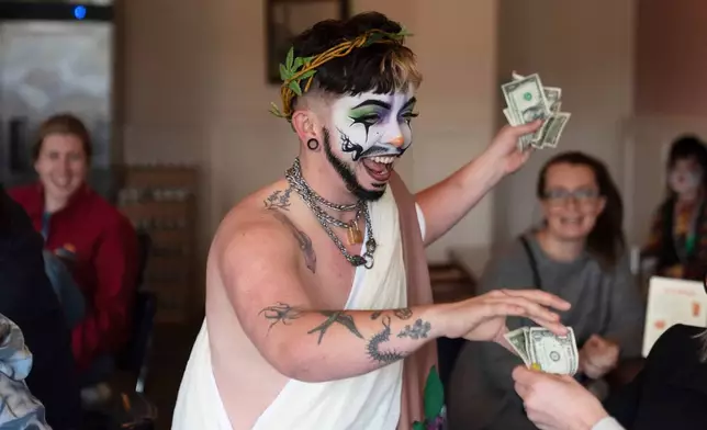 Drag performer Ed Du'Bull receives money from audience members during a "blaze and praise" drag brunch at Bar Carlo on Sunday, April 20, 2025, in Portland, Ore. (AP Photo/Jenny Kane)