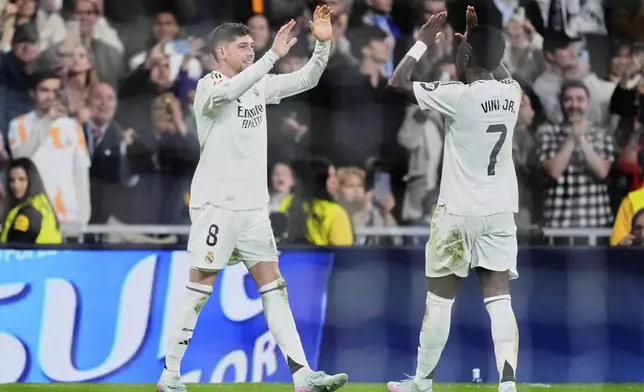 Real Madrid's Federico Valverde, left, is congratulated after scoring his side's first goal by Vinicius Junior during the Spanish La Liga soccer match between Real Madrid and Athletic Bilbao at the Santiago Bernabeu stadium in Madrid, Sunday, April 20, 2025. (AP Photo/Manu Fernandez)