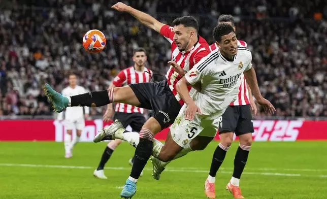 Real Madrid's Jude Bellingham (5) and Athletic Bilbao's Aitor Paredes fight for the ball during the Spanish La Liga soccer match between Real Madrid and Athletic Bilbao at the Santiago Bernabeu stadium in Madrid, Sunday, April 20, 2025. (AP Photo/Manu Fernandez)