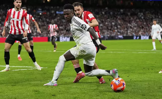 Real Madrid's Vinicius Junior, front, and Athletic Bilbao's Andoni Gorosabel vie for the ball during the Spanish La Liga soccer match between Real Madrid and Athletic Bilbao at the Santiago Bernabeu stadium in Madrid, Sunday, April 20, 2025. (AP Photo/Manu Fernandez)