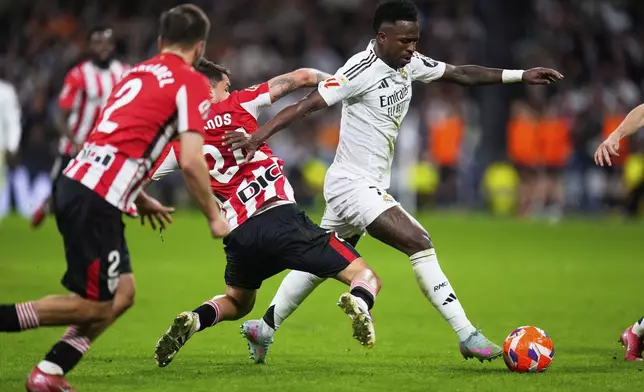 Real Madrid's Vinicius Junior, right, is challenged by Athletic Bilbao's Benat Prados during the Spanish La Liga soccer match between Real Madrid and Athletic Bilbao at the Santiago Bernabeu stadium in Madrid, Sunday, April 20, 2025. (AP Photo/Manu Fernandez)