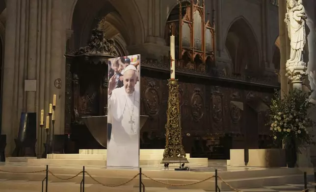 A poster showing Pope Francis has been installed inside Notre Dame cathedral, following the Vatican's announcement of his death, Monday, April 21, 2025 in Paris. (AP Photo/Thibault Camus)