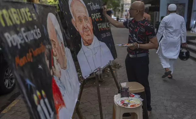 An Indian artist Sagar Kambli makes a painting of Pope Francis as a mark of tribute on a sidewalk in Mumbai, India, Monday, April 21, 2025. (AP Photo/Rafiq Maqbool)