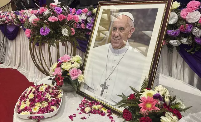 A portrait of Pope Francis is displayed for the people to offer their respects, following the announcement of his death, during a multi-faith assembly at the Sacred Heart Cathedral in New Delhi, India, Monday, April 21, 2025. (AP Photo/Piyush Nagpal)