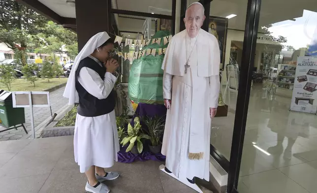 A Catholic nun prays in front of a cutout of Pope Francis in Yogyakarta, Indonesia, Monday, April 21, 2025. (AP Photo/Slamet Riyadi)