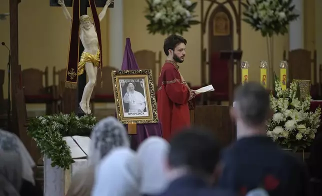 Parishioners attend a service sitting in front of a photo of the late Pope Francis after the news of his death at the Cathedral of the Immaculate Conception in Moscow, Russia, Monday, April 21, 2025. (AP Photo/Pavel Bednyakov)