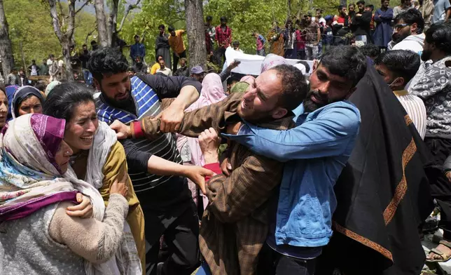 Relatives console the brother, in brown cloak, of Adil Hussain Shah, a daily-wage worker, who died when militants indiscriminately opened fire on a crowd of mainly tourists on Tuesday, at his village Hapatnar, about 20 km (13 miles) from Pahalgam where the incident took place, Indian controlled Kashmir, Wednesday, April 23, 2025. (AP Photo/Dar Yasin)