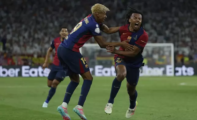 Barcelona's Jules Kounde, right, celebrates after scoring his side's third goal during the Spanish Copa del Rey final soccer match between Barcelona and Real Madrid at Estadio de La Cartuja stadium in Seville, Spain, Sunday, April 27, 2025. (AP Photo/Joan Monfort)
