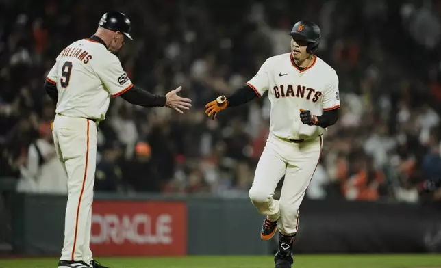 San Francisco Giants' Wilmer Flores, right, celebrates with third base coach Matt Williams after hitting a solo home run during the sixth inning of a baseball game against the Milwaukee Brewers, Monday, April 21, 2025, in San Francisco. (AP Photo/Godofredo A. Vásquez)