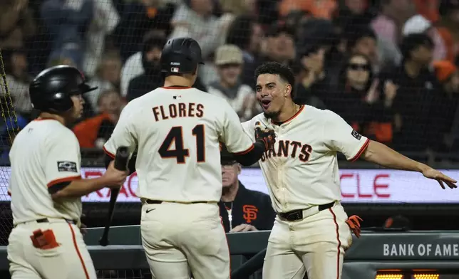 San Francisco Giants' Wilmer Flores (41) is congratulated by shortstop Willy Adames, right, after hitting a solo home run during the sixth inning of a baseball game against the Milwaukee Brewers, Monday, April 21, 2025, in San Francisco. (AP Photo/Godofredo A. Vásquez)