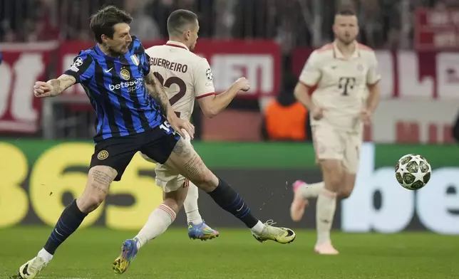 Inter Milan's Francesco Acerbi, front left, duels for the ball with Bayern's Raphael Guerreiro during the Champions League quarterfinals first leg soccer match between FC Bayern Munich and Inter Milan, at the Allianz Arena in Munich, Germany, Tuesday, April 8, 2025. (AP Photo/Matthias Schrader)