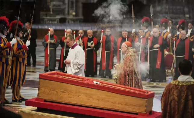 Cardinal Camerlengo Kevin Joseph Farrell, center right, spreads incense around the body of Pope Francis inside St. Peter's Basilica at the Vatican, Wednesday, April 23, 2025, where he will lie in state for three days. (AP Photo/Alessandra Tarantino)