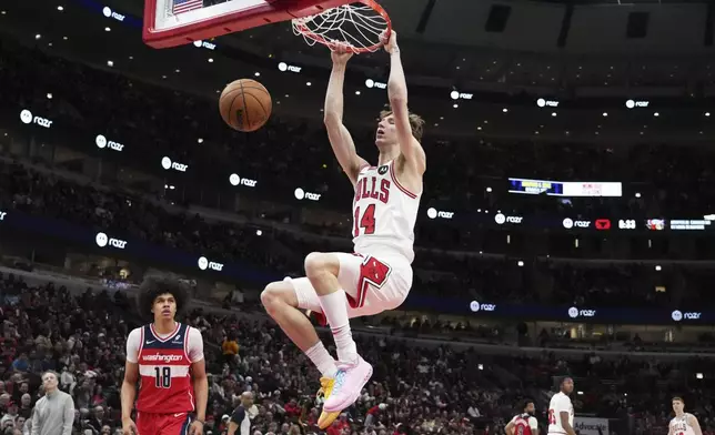 Chicago Bulls forward Matas Buzelis (14) hangs from the rim after dunking during the second half of an NBA basketball game against the Washington Wizards in Chicago, Friday, April 11, 2025. (AP Photo/Nam Y. Huh)