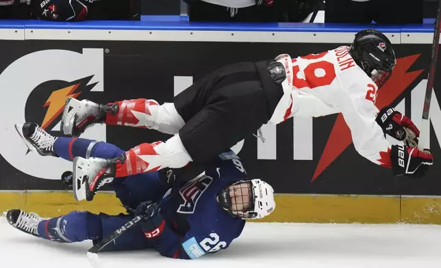 Canada's Marie-Philip Poulin falls over United States' Kendall Coyne during the gold medal match between Canada and United States at the Women's Ice Hockey Championships in Ceske Budejovice, Czech Republic, Sunday, April 20, 2025. (AP Photo/Petr David Josek)