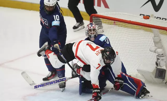 Canada's Laura Stacey falls in front of United States' Laila Edwards amd goalkeeper Gwyneth Philips during the gold medal match between Canada and United States at the Women's Ice Hockey Championships in Ceske Budejovice, Czech Republic, Sunday, April 20, 2025. (AP Photo/Petr David Josek)