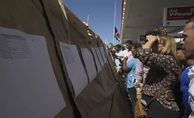 People read lists of survivors as crews search for others trapped at the Jet Set nightclub after its roof collapsed during a merengue concert in Santo Domingo, Dominican Republic, Tuesday, April 8, 2025. (AP Photo/Ricardo Hernandez)
