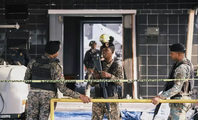 Soldiers guard access to the area while rescue workers search for survivors at the Jet Set nightclub after its roof collapsed two nights prior during a merengue concert in Santo Domingo, Dominican Republic, Wednesday, April 9, 2025. (AP Photo/Ricardo Hernandez)