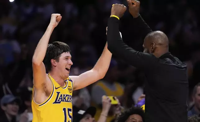 Los Angeles Lakers guard Austin Reaves, left, and forward LeBron James celebrate at the bench during the second half of an NBA basketball game against the Houston Rockets Friday, April 11, 2025, in Los Angeles. (AP Photo/Mark J. Terrill)