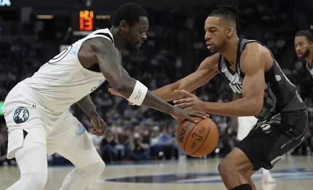 Minnesota Timberwolves forward Julius Randle, left, works toward the basket as Brooklyn Nets forward Tosan Evbuomwan, right, defends during the first half of an NBA basketball game, Friday, April 11, 2025, in Minneapolis. (AP Photo/Abbie Parr)