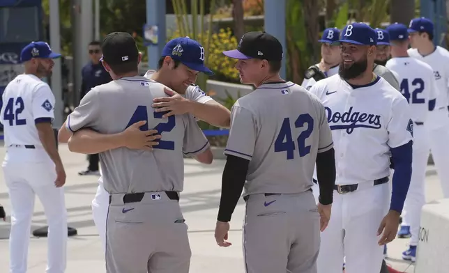 Los Angeles Dodgers' Shohei Ohtani, left, hugs members of the Colorado Rockies at Dodger Stadium during an event to commemorate Jackie Robinson Day before a baseball game Tuesday, April 15, 2025, in Los Angeles. (AP Photo/Damian Dovarganes)