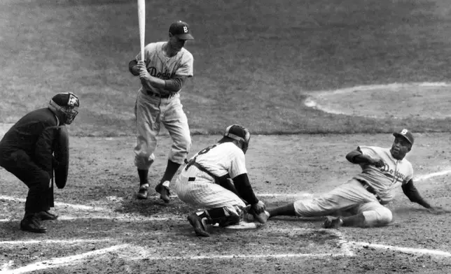 FILE - Brooklyn Dodgers' Jackie Robinson safely steals home plate under the tag of New York Yankees catcher Yogi Berra as pinch-hitter Frank Kellert looks on in the eighth inning of the World Series opener at New York's Yankee Stadium, Sept. 28, 1955. (AP Photo/John Rooney, File)