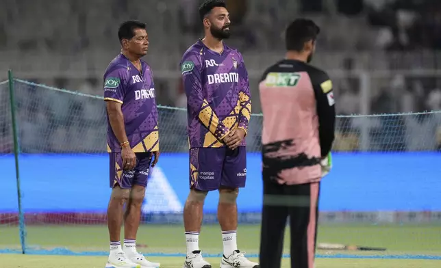 Kolkata Knight Riders coach Chandrakant Pandit, left, and Varun Chakravarthy observe a moment of silence in solidarity with the victims of the recent terror attack in Kashmir before the Indian Premier League cricket match between Kolkata Knight Riders and Punjab Kings at Eden Gardens in Kolkata in Kolkata , India, Saturday, April 26, 2025. (AP Photo/Bikas Das)