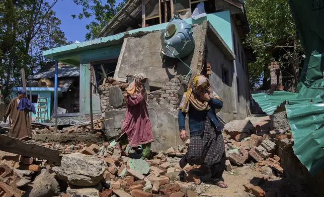 Kashmiri villager women walk past the blown-up family home of Asif Shiekh, a militant who officials all is involved in the deadly attack on tourists in Pahalgam, at Monghama village in Tral, south of Srinagar, Indian controlled Kashmir, Friday, April 25, 2025. (AP Photo/Dar Yasin)