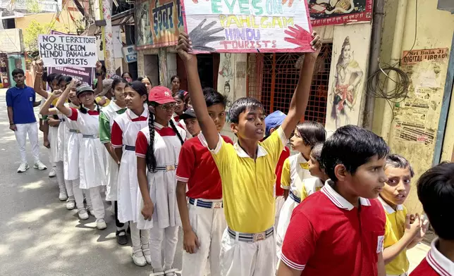 Schoolchildren walk with candles and banners during a protest and solidarity march against the killing of tourists by militants near Pahalgam in Indian controlled Kashmir, in the northern Indian state of Uttar Pradesh Saturday, April 26, 2025. (AP Photo/Rajesh Kumar Singh)
