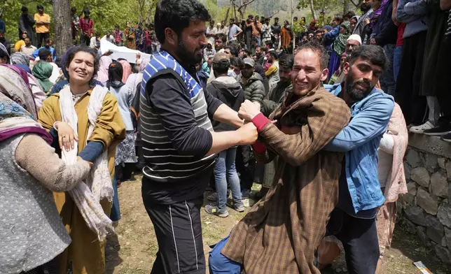 Relatives console the brother, in brown cloak, of Adil Hussain Shah, a daily-wage worker, who died when militants indiscriminately opened fire on a crowd of mainly tourists on Tuesday, at his village Hapatnar, about 20 km (13 miles) from Pahalgam where the incident took place, Indian controlled Kashmir, Wednesday, April 23, 2025. (AP Photo/Dar Yasin)