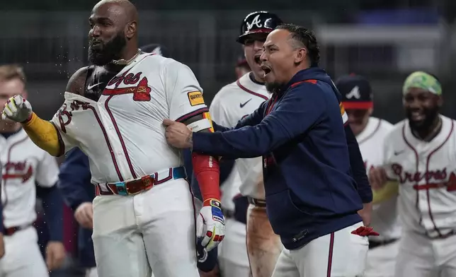Atlanta Braves designated hitter Marcell Ozuna (20) celebrates with the team after he hit a walk-off two-run homer against the Philadelphia Phillies in the 11th inning of a baseball game after a rain delay, Friday, April 11, 2025, in Atlanta. (AP Photo/Mike Stewart)