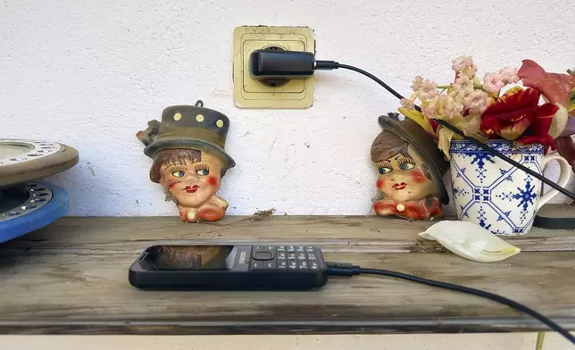 A mobil phone is charging outdoors at the home Zoica Roth, 83, in the village of Saschiz, in Romania's central Transylvania region, Friday, April 25, 2025. (AP Photo/Stephen McGrath)