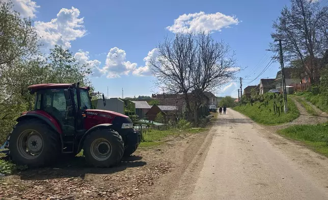 People walk on a road in the village of Saschiz, in Romania's central Transylvania region, Friday, April 25, 2025. (AP Photo/Stephen McGrath)