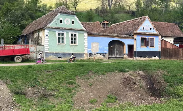 Children ride bicycles in the village of Floresti, in Romania's central Transylvania region, Thursday, April 24, 2025. (AP Photo/Stephen McGrath)