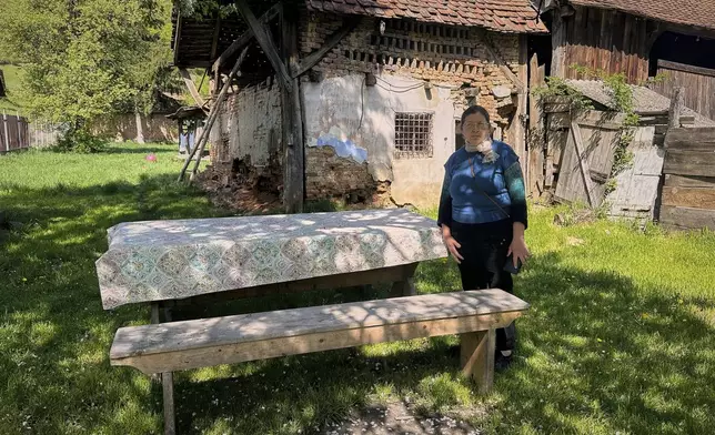 Liliana Cosurean, 54, stands in the yard of her home, in the village of Floresti, in Romania's central Transylvania region, Thursday, April 24, 2025. (AP Photo/Stephen McGrath)