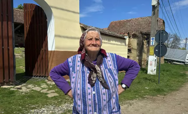 Zoica Roth, 83, stands outside her house in the village of Saschiz, in Romania's central Transylvania region, Friday, April 25, 2025. (AP Photo/Stephen McGrath)