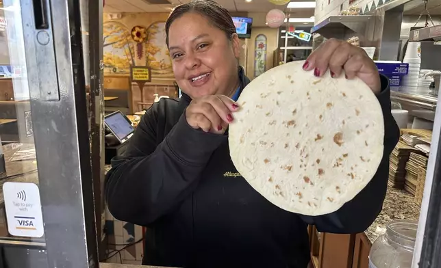 Jasmine Perez holds up a fresh tortilla while standing at the pickup window inside Garcia's Kitchen in Albuquerque, New Mexico, on Thursday, April 10, 2025. (AP Photo/Susan Montoya Bryan)