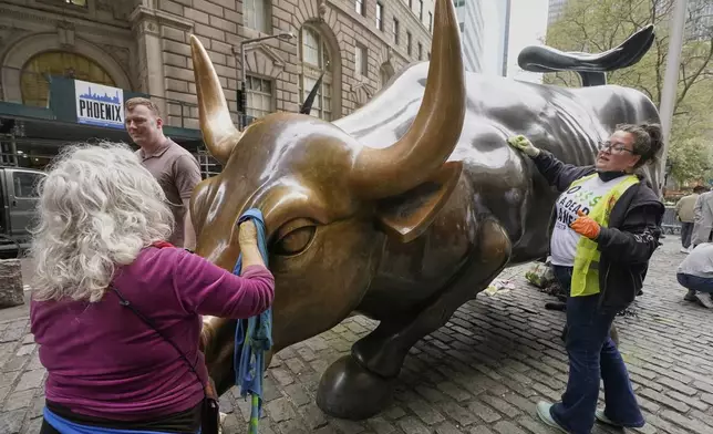 Members of Extinction Rebellion clean Arturo Di Modica's "Charging Bull" sculpture that they defaced during a demonstration in New York, Tuesday, April 22, 2025. (AP Photo/Richard Drew)