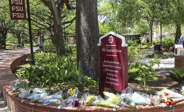 Flowers placed by students sit next to a sign for the Florida State Student Union building, Tallahassee, Fla., Friday, April 18, 2025. (AP Photo/Gary McCullough)