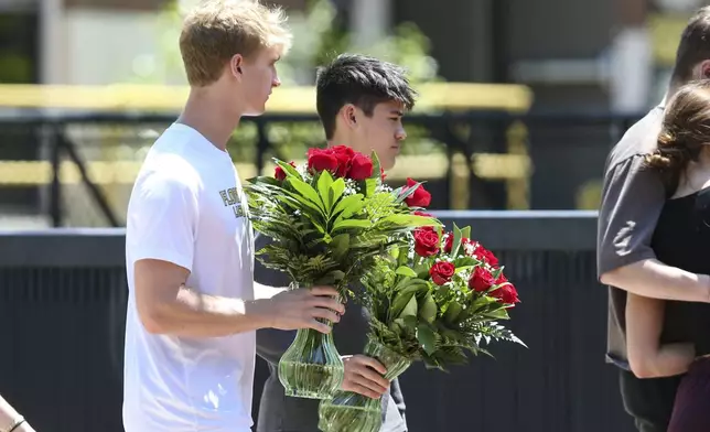 Students carry flowers near the Florida State Student Union building, Tallahassee, Fla., Friday, April 18, 2025. (AP Photo/Gary McCullough)