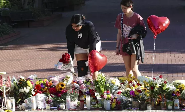 Students place flowers on a stretch of sidewalk near the center of the Florida State campus in sight of the Student Union building, Tallahassee, Fla., Friday, April 18, 2025. (AP Photo/Gary McCullough)