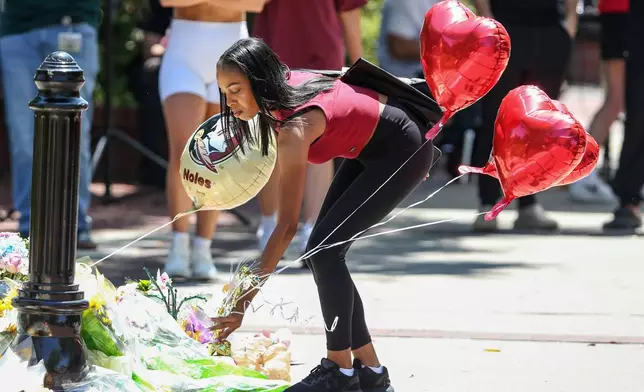 A student places heart-shaped balloons near the Florida State Student Union building, Tallahassee, Fla., Friday, April 18, 2025. (AP Photo/Gary McCullough)