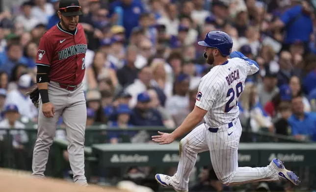 Chicago Cubs' Michael Busch (29), right, slides safely past Arizona Diamondbacks third baseman Eugenio Suárez (28) during the fourth inning of a baseball game Friday, April 18, 2025, in Chicago. (AP Photo/Erin Hooley)