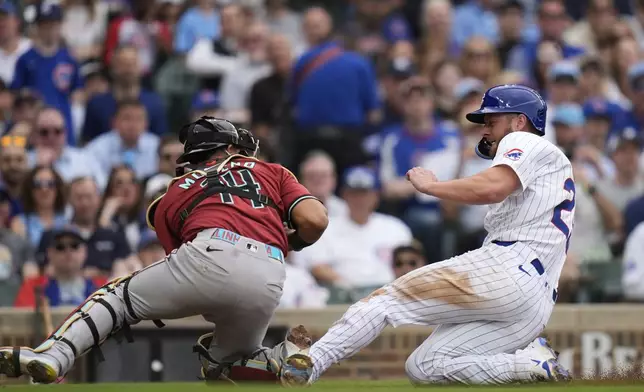 Chicago Cubs' Michael Busch, right, is tagged out by Arizona Diamondbacks catcher Gabriel Moreno (14) during the fourth inning of a baseball game Friday, April 18, 2025, in Chicago. (AP Photo/Erin Hooley)