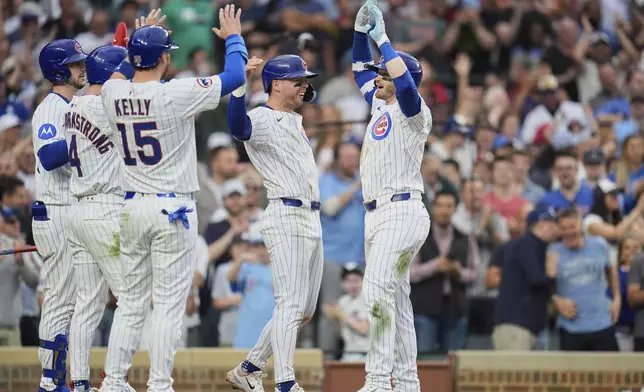 Chicago Cubs' Ian Happ, right, high-fives Nico Hoerner after hitting a grand slam during the seventh inning of a baseball game against the Arizona Diamondbacks, Friday, April 18, 2025, in Chicago. (AP Photo/Erin Hooley)