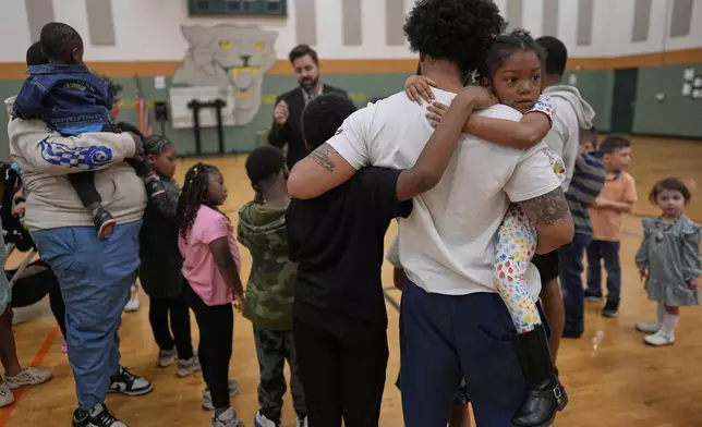 Ronald Lunsford, holds his childern Parker Scroggins, right, and Maleachi Yancey, standing left, as River Church Cincinnati pastor Cory Bowman, who is Vice President JD Vance's half brother and Cincinnati mayoral candidate, preaches during River Church Cincinnati Easter worship service in the Hays Porter Elementary School gym Sunday, April 20, 2025, in Cincinnati. (AP Photo/Carolyn Kaster)