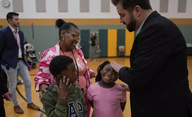 River Church Cincinnati pastor Cory Bowman, who is Vice President JD Vance's half brother and Cincinnati mayoral candidate, right, prays for healing over Ja'Sani Baltimore, 5, second from right, Kevon Winfield, 6, with Terra Williams during Easter worship service at the Hays Porter Elementary School gym Sunday, April 20, 2025, in Cincinnati. (AP Photo/Carolyn Kaster)