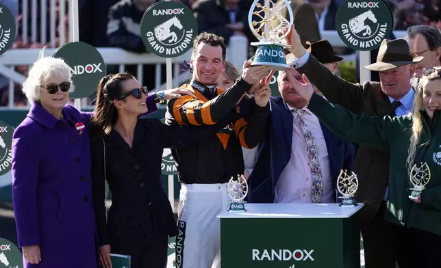 Jockey Patrick Mullins holds up the trophy after winning the Grand National Handicap Steeple Chase race aboard Nick Rockett, on the third day of the Grand National Horse Racing meeting at Aintree racecourse, near Liverpool, England, Saturday, April 5, 2025. (Peter Byrne/PA via AP)