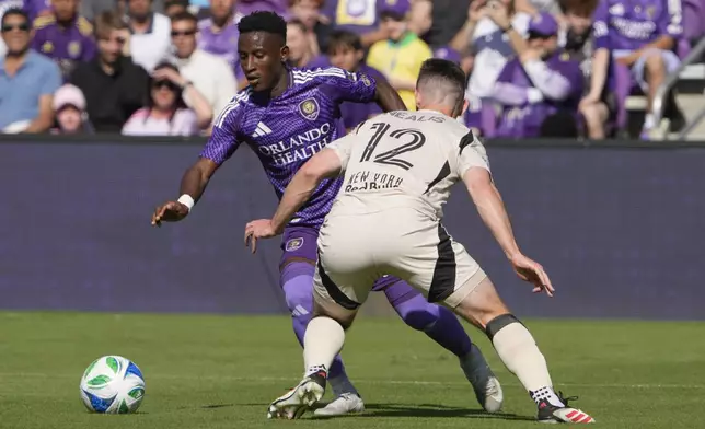 Orlando City forward Ivan Angulo, left, makes a move to get past New York Red Bulls defender Dylan Nealis (12) during the first half of an MLS soccer match, Saturday, April 12, 2025, in Orlando, Fla. (AP Photo/John Raoux)