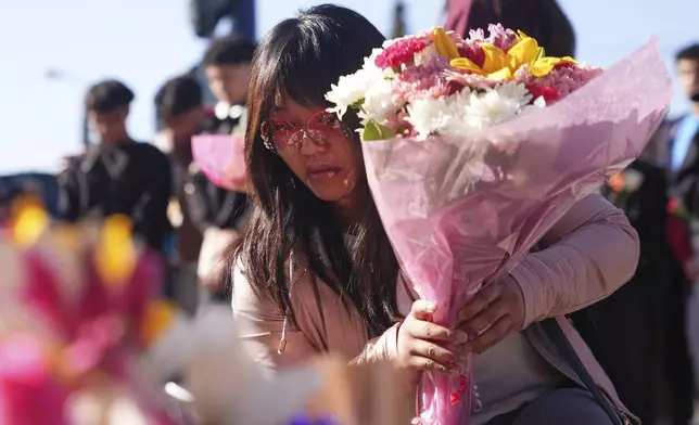 A woman places flowers at a memorial after a vehicle drove into a crowd during a Filipino heritage festival in Vancouver, British Columbia, Sunday, April 27, 2025. (AP Photo/Lindsey Wasson)