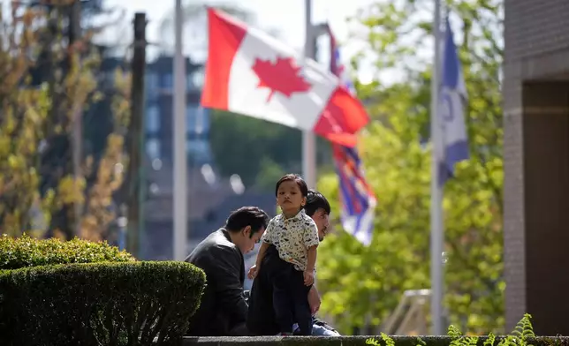 A young child and man listen from outside St. Mary's Parish during afternoon mass that was at capacity, after multiple people that were stuck by a car on Saturday night were killed at a Filipino heritage festival in Vancouver, British Columbia, Sunday, April 27, 2025. (Darryl Dyck/The Canadian Press via AP)